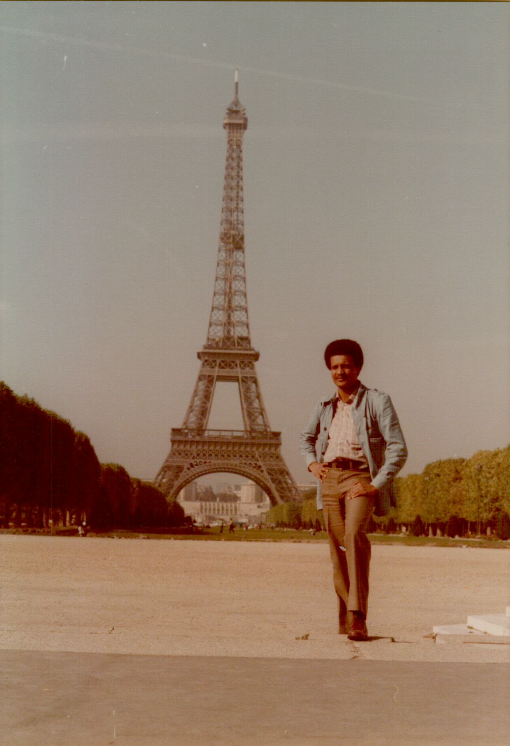 Amha standing confidently in front of the Eiffel Tower on the Champ de Mars